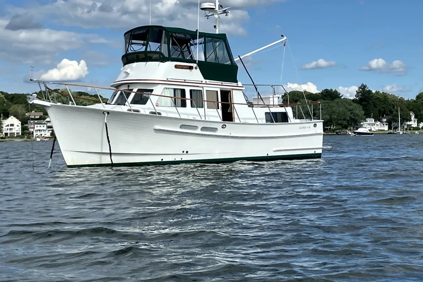 A Monk 36 trawler at anchor off a wooded shore