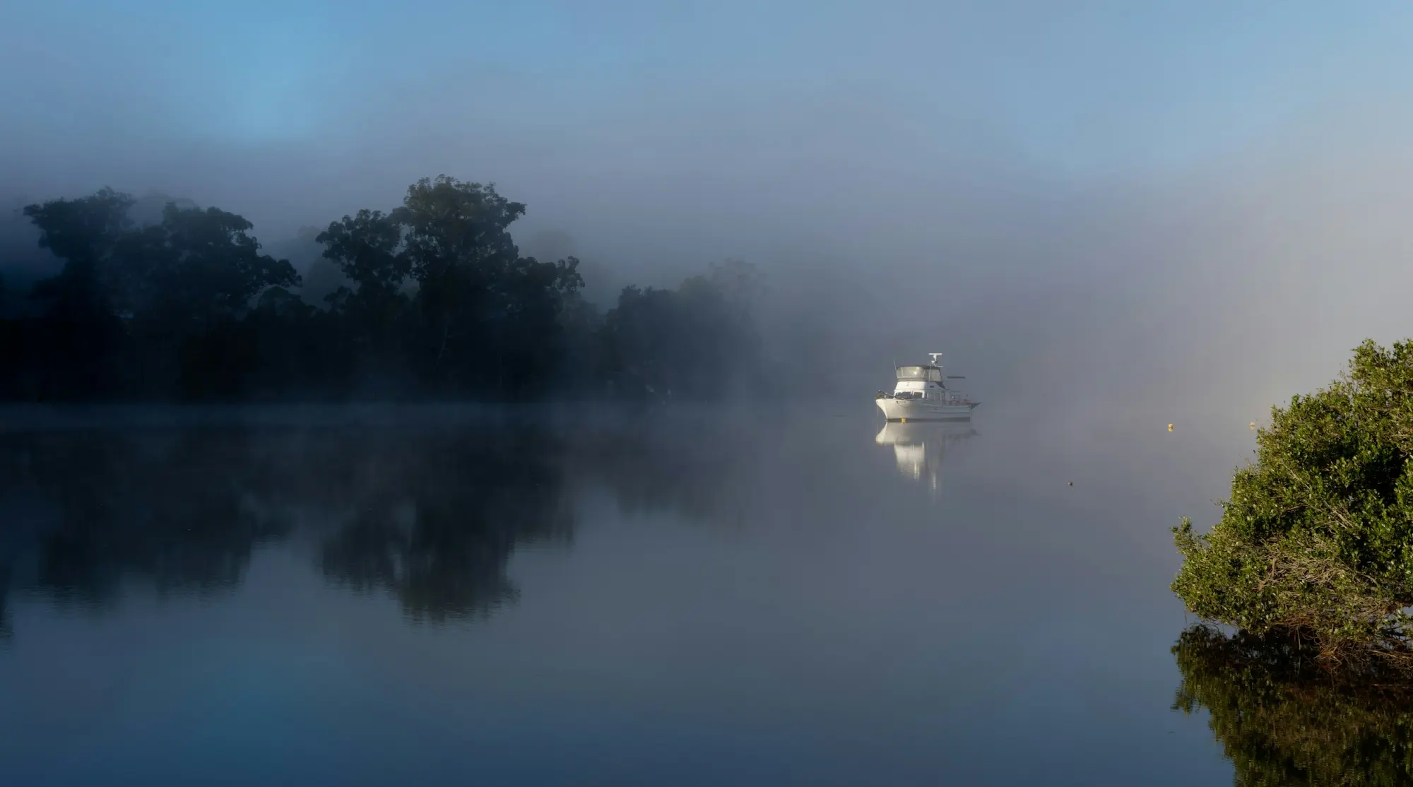 A classic trawler on a mooring in a misty river at dawn